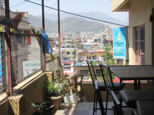 a balcony with a table and chairs and a view of a city at STUPA VIEW INN in Kathmandu