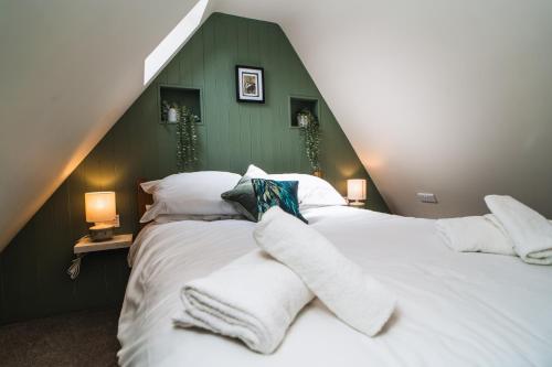 a bedroom with a large white bed with a green wall at Otter's Pocket in Blandford Forum