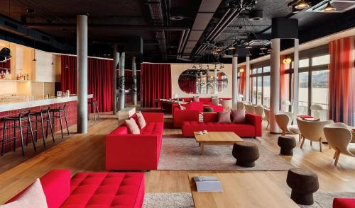 um restaurante com sofás vermelhos e um bar em HERMITAGE Lake Lucerne - Beach Club & Lifestyle Hotel em Lucerna