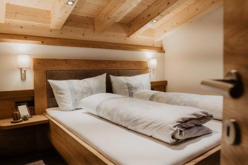 a bedroom with a large white bed with wooden ceilings at Ferienhaus Bergler Hoamat in Navis