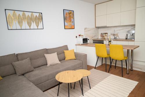 a living room with a couch and a table and yellow chairs at Muki Park Lake in Tuzla