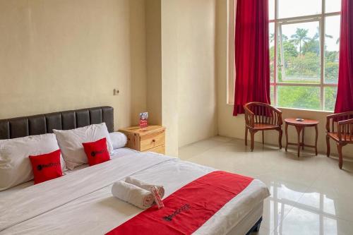 una camera da letto con un grande letto con cuscini rossi e bianchi di RedDoorz near Universitas Merdeka Malang 2 a Malang