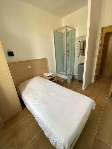 a bedroom with a white bed and a shower at Hôtel Raphael Prado in Marseille