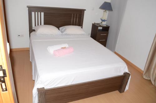 Un dormitorio con una cama con una toalla rosa. en Apartamento Terra Branca, en Praia