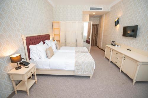 a bedroom with a large white bed and a desk at RIVER INN RESORT AND SPA in Nabran