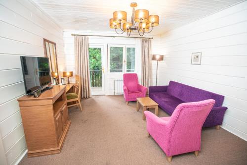 a living room with a purple couch and two pink chairs at RIVER INN RESORT AND SPA in Nabran