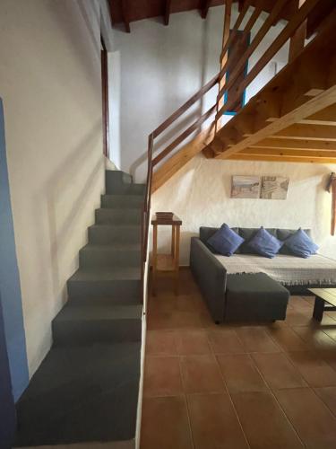 een woonkamer met een bank en een trap bij Can Joan Barber, 1 in La Mola