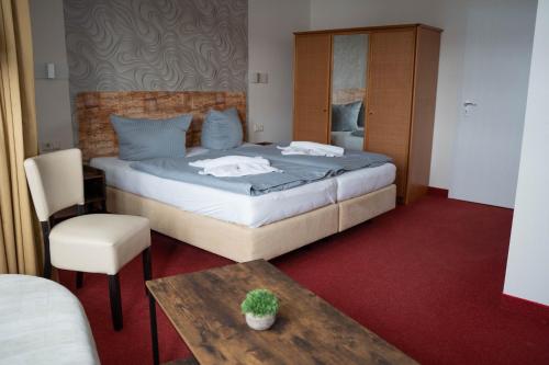 a bedroom with a bed and a table and a chair at REGIOHOTEL Am Brocken Schierke in Schierke