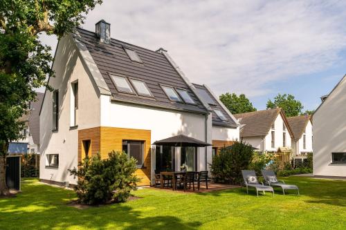 a house with a yard with chairs and a patio at Haus Sandnelke - Domizil am Ostseewald in Zingst