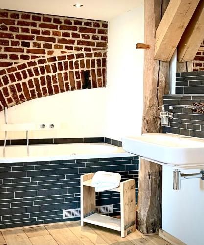 a bathroom with a sink and a brick wall at Landgoed Moerslag in Sint Geertruid