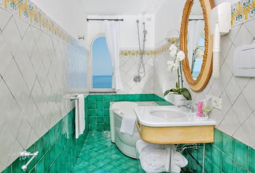 a green and white bathroom with a sink and a tub at Hotel L'Ancora in Positano