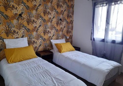 a bedroom with two beds and a wall with floral wallpaper at Maison confortable à Coltines 80 m² avec jardin spacieux in Coltines