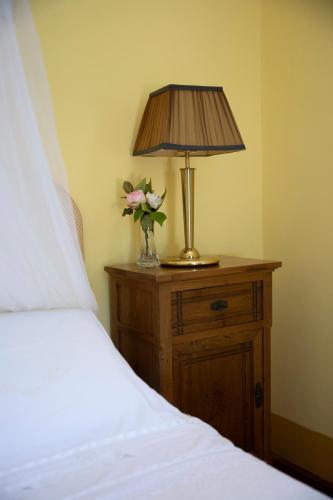 a table with a lamp and a vase of flowers on a bed at Agriturismo Petrara in Simeri