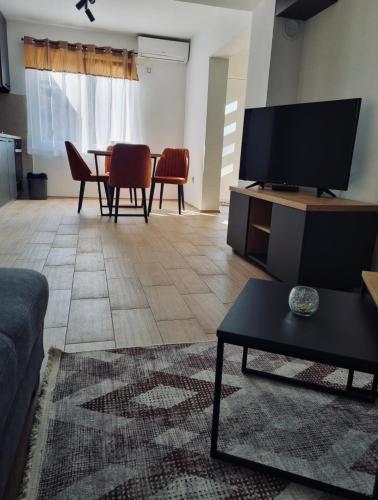a living room with a tv and a table with chairs at OM Apartment in Podgorica