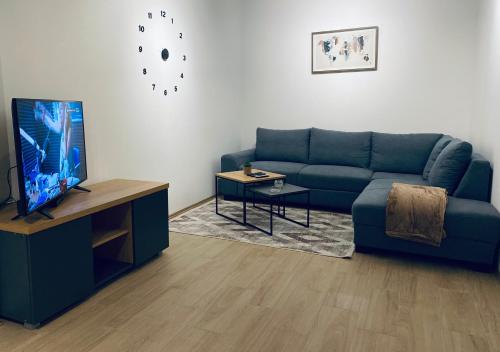 sala de estar con sofá azul y TV en OM Apartment, en Podgorica