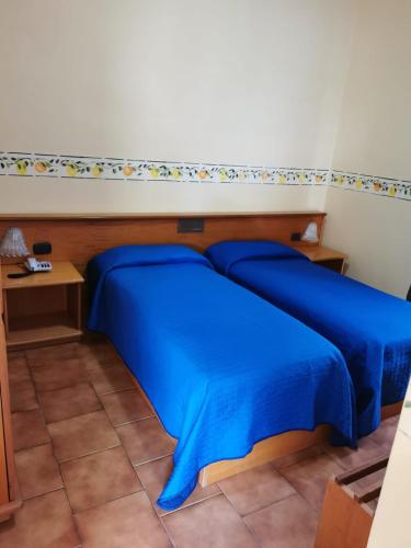 a bed with blue sheets in a room at Hotel San Pietro in Letojanni