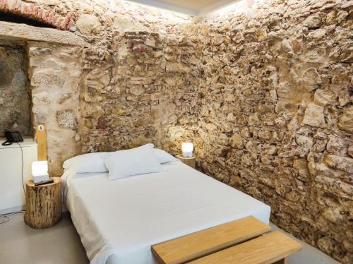 1 dormitorio con cama y pared de piedra en Casa da Sé Cathedral Suites, en Coímbra