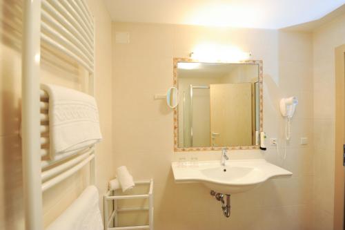 a white bathroom with a sink and a mirror at Landhotel Latscherhof in Laces