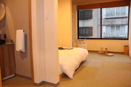 una camera con un letto e una finestra con una finestra di 城崎温泉 小宿 紬 tsumugi a Toyooka