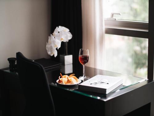 a table with a glass of wine and a plate of food at JW Marriott Hotel & Suites Saigon, The Apartments in Ho Chi Minh City