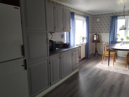 a kitchen with white cabinets and a table in a room at Hus på landet nära sjö in Berga