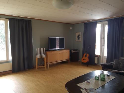 a living room with a flat screen tv and a table at Hus på landet nära sjö in Berga