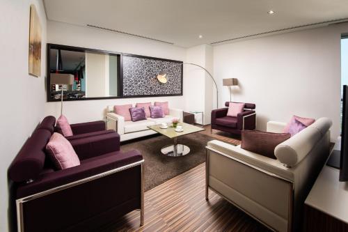 a living room with two couches and a table at Pullman Dubai Jumeirah Lakes Towers in Dubai