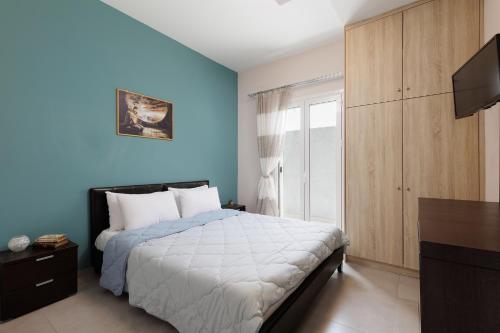 Dormitorio azul con cama y TV en Planet Villas by Konnect - Shared BBQ & Garden, en Ýpsos