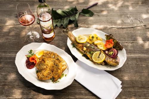 a table with two plates of food and a glass of wine at Wirtshaus Jagawirt in Sommereben