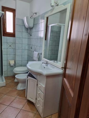 a bathroom with a sink and a toilet and a mirror at Appartamenti Quilici in Santa Maria Navarrese