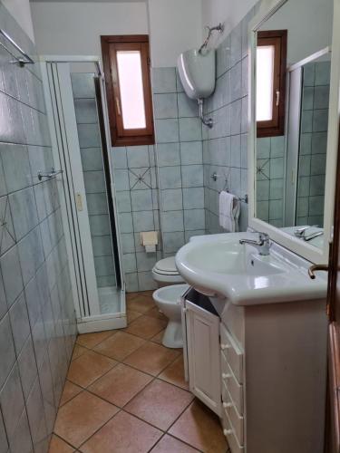a bathroom with a sink and a toilet and a mirror at Appartamenti Quilici in Santa Maria Navarrese