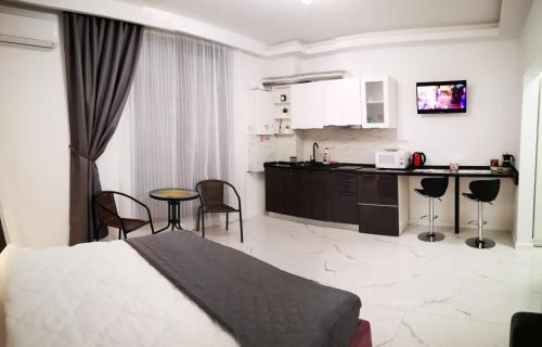 ein Schlafzimmer mit einem Bett und eine Küche mit Stühlen in der Unterkunft Promenada Beach Residence in Mamaia Nord – Năvodari