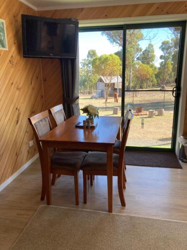 a wooden dining room table with chairs and a flat screen tv at Winganah Cottage in Murdunna