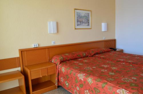 a hotel room with a bed with a red bedspread at Linda in Can Pastilla