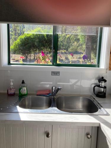 a sink in a kitchen with a window above it at Winganah Cottage in Murdunna