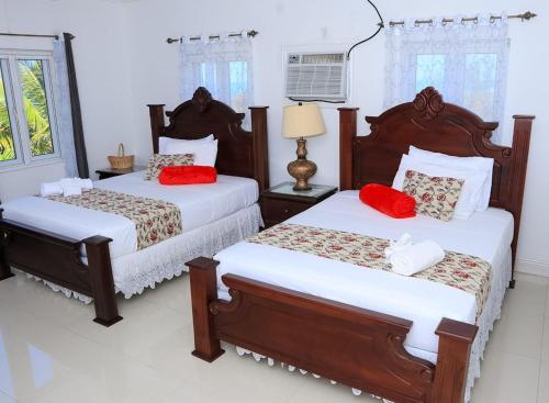 a bedroom with two beds with red pillows at Redknot Manor Guest house/Hotel in Matthew Town