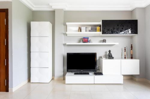 a living room with a television and white cabinets at La Casita Gris in Sauzal