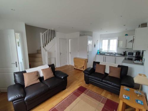 a living room with two black leather couches and a kitchen at Sea Dragon in Rye