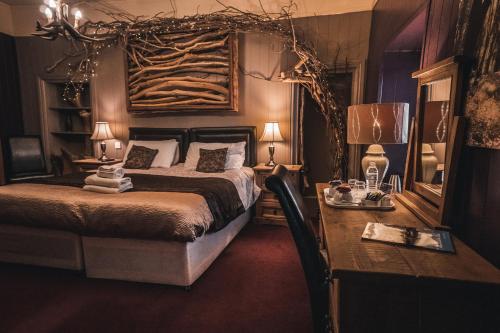 a bedroom with a bed and a desk and a table with lamps at No1 Hotel in Wooler