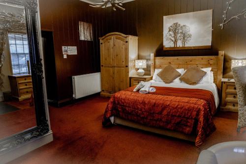 a bedroom with a large bed with a red bedspread at No1 Hotel in Wooler