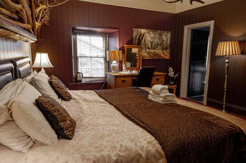 een slaapkamer met een groot bed en een bureau bij No1 Hotel in Wooler