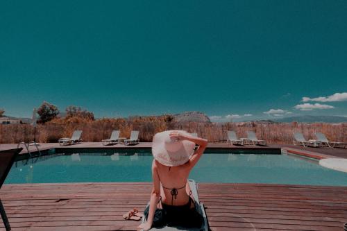 a woman sitting on a deck next to a swimming pool at Palacio del Sol Luxury Apartments in Nafplio