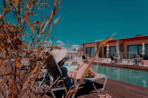 a woman sitting in a chair next to a swimming pool at Palacio del Sol Luxury Apartments in Nafplio