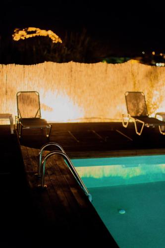 two chairs sitting next to a swimming pool at night at Palacio del Sol Luxury Apartments in Nafplio