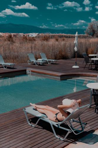 two women laying in lounge chairs next to a swimming pool at Palacio del Sol Luxury Apartments in Nafplio