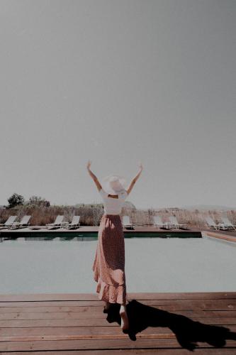 a woman standing on a dock with her arms in the air at Palacio del Sol Luxury Apartments in Nafplio