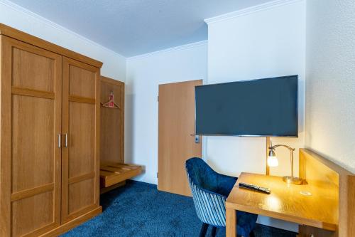 a hotel room with a desk with a tv and a chair at Dorint Parkhotel Siegen in Siegen