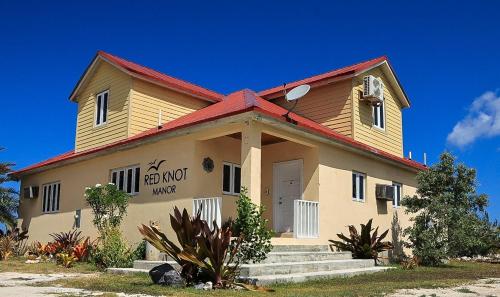 a large yellow building with a red roof at Redknot Manor Guest house/Hotel in Matthew Town