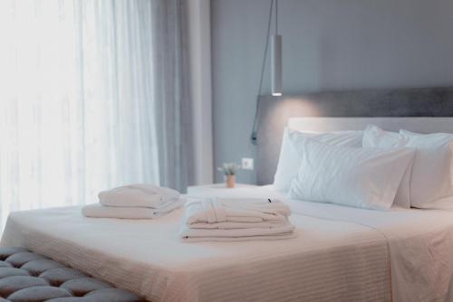 a white bed with two towels on top of it at Palacio del Sol Luxury Apartments in Nafplio