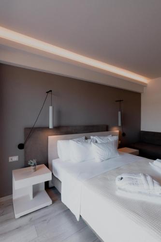 a bedroom with two white beds and a table at Palacio del Sol Luxury Apartments in Nafplio
